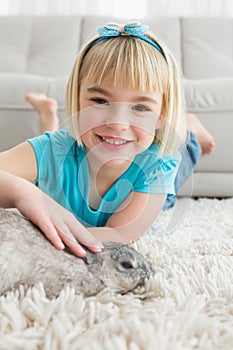 Little girl lying on rug stroking the rabbit