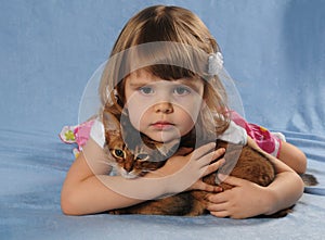 Little girl lying with somali kitten ruddy color