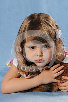 Little girl lying with somali kitten ruddy color