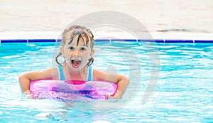 Little girl lying in swimming pool learning to swim on inflatable circle. Summer holidays, heat and water