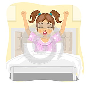 Little girl lying waking up stretching and yawning lying on bed