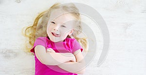 Little girl lying on white wooden floor