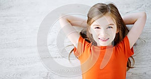 Little girl lying on white wooden floor