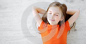 Little girl lying on white wooden floor