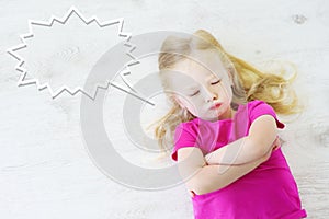 Little girl lying on white wooden floor with a speech bubble above her head