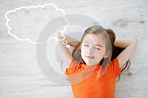 Little girl lying on white wooden floor with a speech bubble above her head