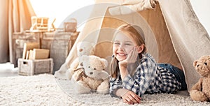 Little girl lying in wigwam with teddies