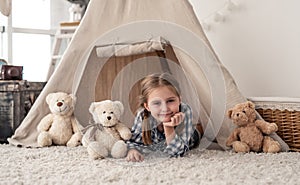 Little girl lying in wigwam with teddies