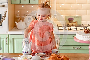 Little girl made Cup of tea with cake in kitchen.festive lunch.playing with kids