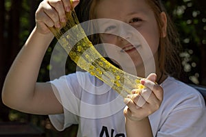 a little girl made a slime and plays with it, stretches it and shows the texture of a transparent slime with decorations