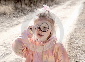 Little girl  with a magnifying glass, investigate  details of nature . outdoor kids activity and learning concept