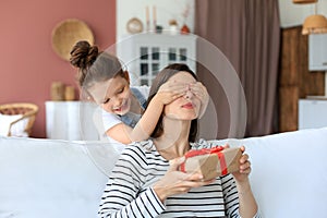 Little girl make birthday present to excited parent , smiling little child congratulate give gift box