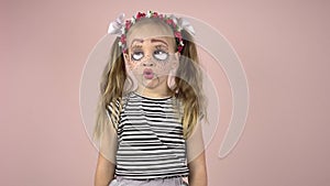 A little girl with make-up on her face depicts puppet grimaces. Carnival costume.