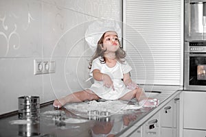 Little girl makes dough on kitchen with rolling pin