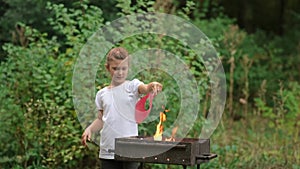 A little girl makes a fire in the grill. Family picnic in the Park