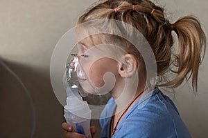 Little girl makes inhalation with a nebulizer at home, sitting on a chair. Portable apparatus for obstruction, bronchial asthma