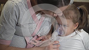 Little girl makes inhalation using a compressor inhaler while sitting on a sofa. A child in a place with a pregnant