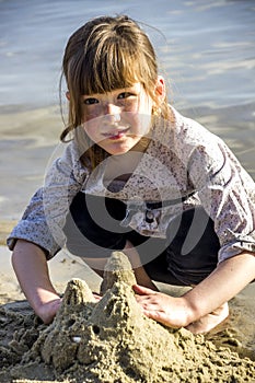 A little girl makes a sand sculture of cat