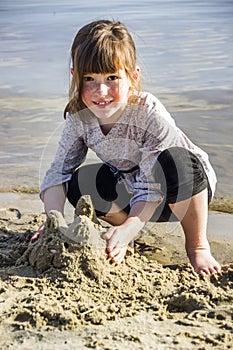 A little girl makes a sand sculture of cat