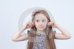 Little girl is making faces. Funny expressions. Having fun. Preschooler in dress on white background.