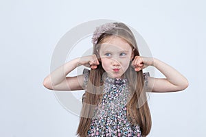 Little girl is making faces. Funny expressions. Having fun. Preschooler in dress on white background.
