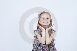 Little girl is making faces. Funny and happy expressions. Having fun. Preschooler in dress on white background.