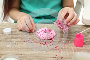 Little girl making homemade slime toy at table