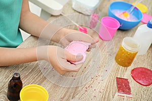 Little girl making homemade slime toy at table