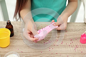 Little girl making homemade slime toy at table