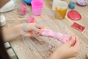 Little girl making homemade slime toy at table