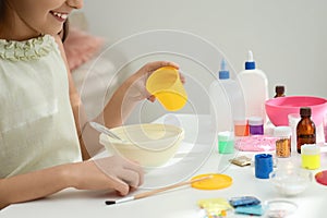 Little girl making homemade slime toy at table