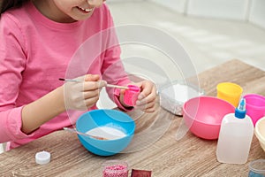 Little girl making homemade slime toy at table