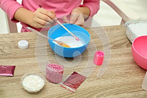 Little girl making homemade slime toy at table