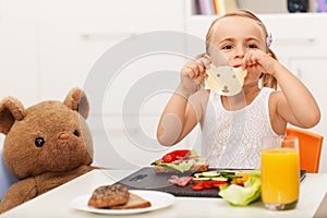 Little girl making a sandwich to her toy bear - having a snack w