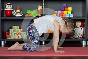 Little girl making yoga cat pose indoor