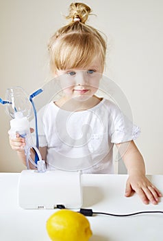 Little girl in a mask for inhalations, making inhalation with nebulizer at home inhaler on the table