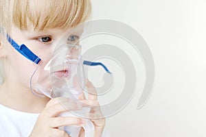 Little girl in a mask for inhalations, making inhalation with nebulizer at home inhaler on the table