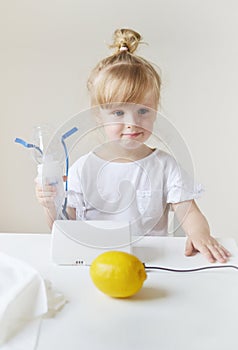 Little girl in a mask for inhalations, making inhalation with nebulizer at home inhaler on the table