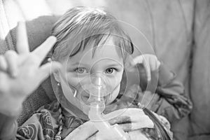 Little girl in a mask, treatments respiratory tract with a nebulizer at home, colorless photo
