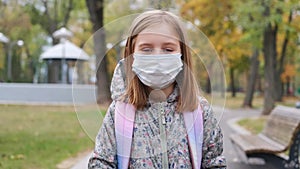 Little girl in mask walking in park