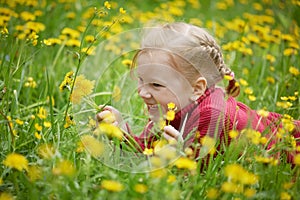 Little girl and meadow with dandelions. Summer day, outdoors