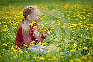 Little girl and meadow with dandelions. Summer day outdoors