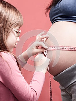 Little girl measuring mother's tummy
