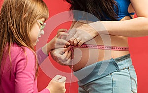 Little girl measuring mother's tummy