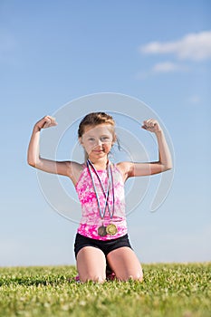 Little girl with medals sitting on the grass and