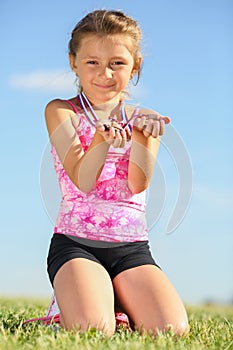 Little girl with medals sitting on the grass on