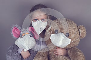 Little girl in a medical mask hugs a soft toys