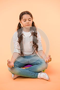 Little girl meditate sitting on penny board on yellow background. Time for yoga. Hipster child activity. Concentration