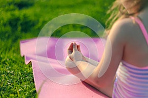 Little girl meditates on a pink rug