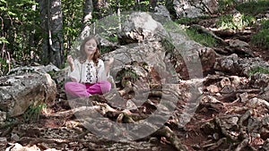 Little girl meditating in the forest